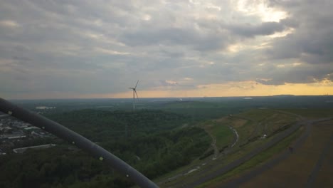 Aerial-view-of-wind-turbine-blades-rotating-at-the-distance-with-beautiful-sunset