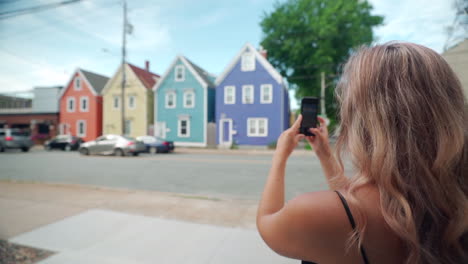 Woman-taking-photo-of-colourful-buildings-on-her-cell-phone-in-Halifax,-Nova-Scotia,-Canada
