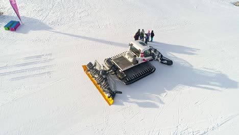 Aerial-shot-of-large-snow-pusher-working-in-snowy-mountains-during-sunlight