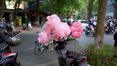 Slow-motion-shot,-Pink-balloons-tied-to-the-scooter,-rush-hour-traffic-in-the-background,-Vietnam