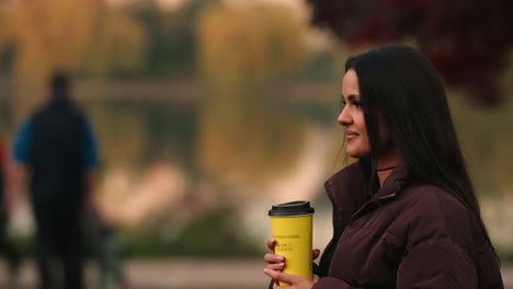 Portrait-Of-A-Pretty-Young-Woman-Walking-On-The-Park-With-A-Coffee-In-Iulius,-Cluj-Napoca,-Romania