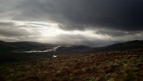 Heftige-Winde-Und-Lichtstrahlen-Durchdringen-Dunkle-Wolken,-Um-Eine-Landschaft-Mit-Süßwasserlochs-Hervorzuheben,-Die-In-Die-Berge-Schottlands-Eingebettet-Sind