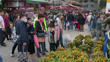 Customers-buy-typical-decorative-Chinese-New-Year-flowers-and-kumquat-trees,-also-known-as-tangerine-trees-at-a-flower-market-street-stall-ahead-of-the-Lunar-Chinese-New-Year-festivities