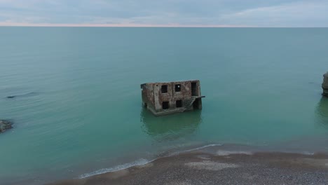 Aerial-view-of-abandoned-seaside-fortification-buildings-at-Karosta-Northern-Forts-on-the-beach-of-Baltic-sea-,-overcast-day,-wide-drone-shot-moving-forward,-tilt-down