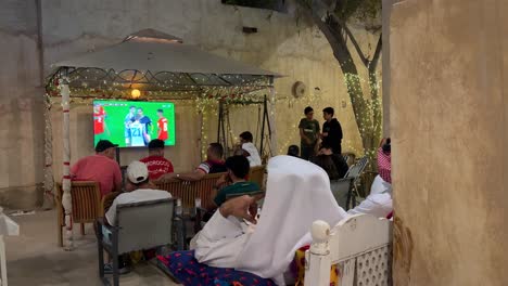 People-are-watching-the-football-game-in-a-traditional-local-café-in-Doha-Qatar-in-Wakra-souq-down-town-old-city-renovated-for-tourism-and-walking-at-night-with-friends-an-family-shopping-street-foods