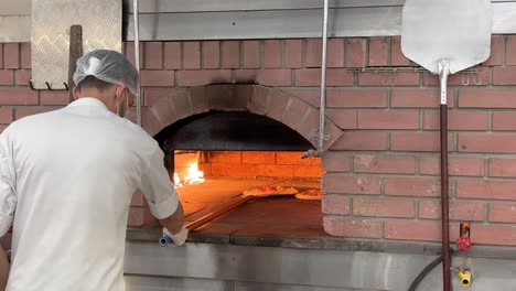 Chef-cook-bake-a-Pizza-bread-in-traditional-local-brick-oven-fire-make-it-hot-warm-area-cooking-skill-rotate-vegetable-margarita-pizza-Italian-food-with-cheese-and-pepperoni