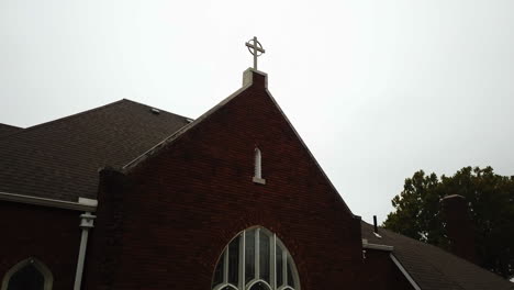 Descending-shot-of-a-cross-ontop-of-a-church-revealing-the-church