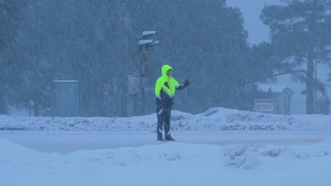Lettischer-Straßenpolizist,-Der-Autoverkehr-Während-Eines-Schweren-Schneesturms-Organisiert,-Bewölkter-Wintertag,-Handferner-Mittlerer-Schuss