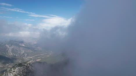 Drone-Flying-through-clouds,-Drone-shot-captures-the-breathtaking-panoramic-view-of-rugged-mountains-and-clouds-at-Termessos-National-Park