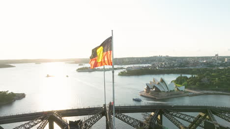 Die-Australische-Flagge-Der-Aborigines-Und-Die-Australische-Blaue-Flagge-Wehen-Bei-Sonnenaufgang-Auf-Der-Hafenbrücke-Von-Sydney-In-New-South-Wales,-Australien