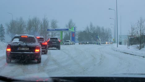 Busy-Neste-petrol-station-with-queues-of-people-refilling-their-cars-in-fear-of-fuel-shortages,-rising-prices,-hype-at-gas-stations,-overcast-winter-day-with-heavy-snowstorm,-wide-handheld-shot