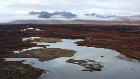 Drone-view-over-dramatic-Icelandic-landscape,-low-cloud-around-mountains
