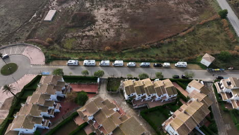 Aerial-Birdseye-view-over-line-of-various-campervans-parked-on-Estartit-beach-waterfront