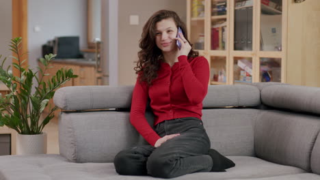 Pretty-caucasian-girl-in-red-cardigan-on-sofa---animated-phone-call,-living-room