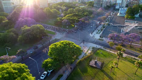 Dolly-in-aerial-view-of-a-group-of-cyclists-with-an-epic-shot-of-the-sun's-rays,-square-full-of-trees-around,-Recoleta-neighborhood
