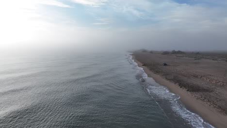 Aerial-drone-flying-above-beach-in-Estartit,-early-morning-sea-fog,-forward