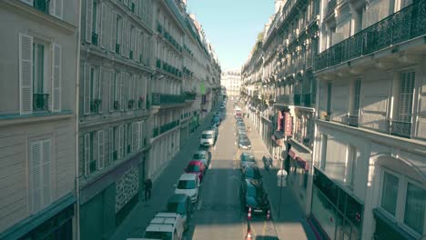 Narrow-street-full-of-vehicles-parked-on-the-sides,-with-Parisian-architecture,-France