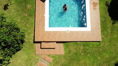 Overhead-Shot-Of-Mother-And-Son-Enjoying-Warm-Water-In-Stunning-Pool-Design