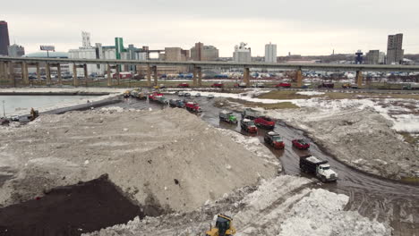 29-December-2022---Aerial-Flying-Over-Snow-Storage-Site-With-Queues-Of-Trucks-Lining-Up-Beside-Buffalo-Highway-In-New-York