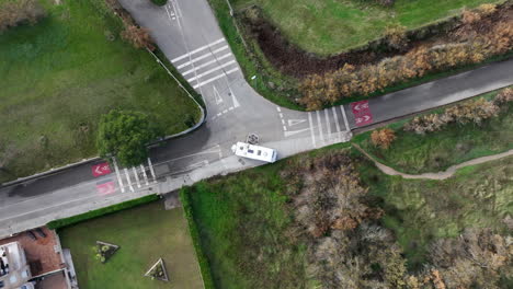 Top-down-aerial-drone-view-of-huge-camper-van-taking-narrow-roundabout,-country
