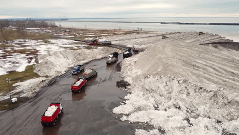 Aerial-view-Aftermath-of-Buffalo-Snowstorm,-trucks-Cleaning-and-removing-massive-pile-of-Snow