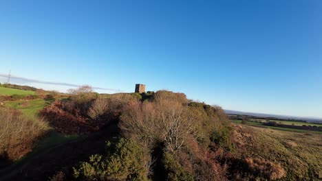 FPV-drone-flying-towards-Billinge-hill-beacon-autumn-Lancashire-farmland-woodland
