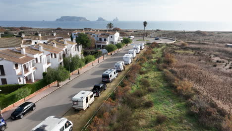 Aerial-flying-over-motorhomes-parked-on-street-next-to-beach,-Costa-Brava,-Spain