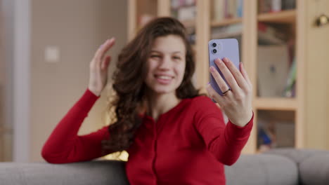 Young-dark-haired-woman-fixes-hair-and-takes-selfie-with-phone-at-home