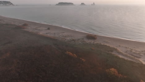 Aerial-tilt-up-over-Costa-Brava-in-foggy-morning,-Medes-Islands-in-background
