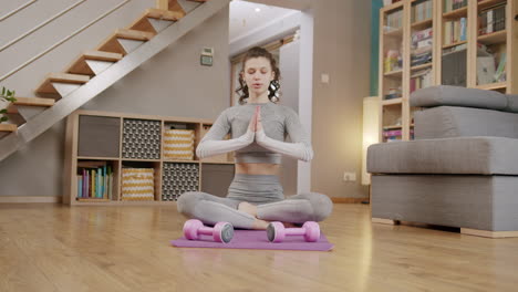 Young-dark-haired-woman-does-yoga-in-lotus-position-at-home,-static