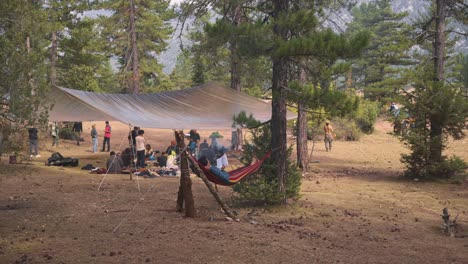 Slowmotion-panning-shot-of-a-woodland-camp-being-setup-with-a-man-sleeping-in-a-hammock