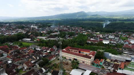 Indonesian-township-with-rooftops-and-smokes,-aerial-drone-view