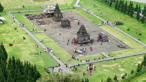 Ancient-stone-temple-surrounded-by-green-meadows,-aerial-orbit-view