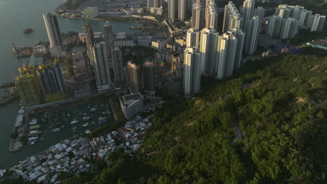 Suspenseful-tilt-up-reveal-shot-of-Yau-Tong-district-with-skyline-of-Hong-Kong-and-mountain-range-during-sunset-time
