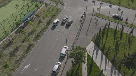 Aerial-tracking-shot-of-cars-stopping-at-lights-with-pedestrians-crossing