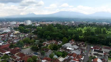 Magelang-town-rooftops-and-mountains-in-horizon,-aerial-drone-view