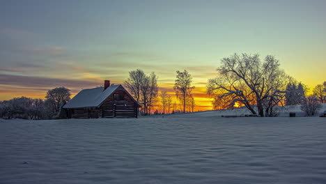 Stunningly-colorful-sunrise-beyond-a-cabin-on-a-winter-landscape---time-lase