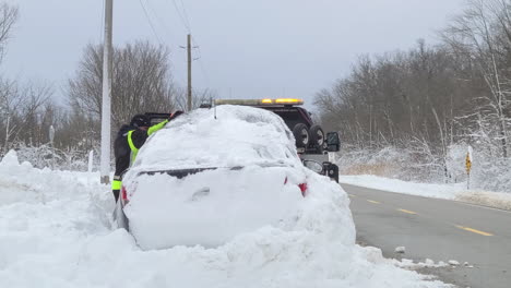 Service-workers-by-snowed-in-car-at-side-of-road-after-storm-in-Canada