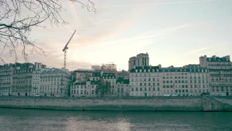 Parisian-architecture-on-the-banks-of-the-Seine-River,-old-and-similar-design-of-buildings,-sunset-in-the-background