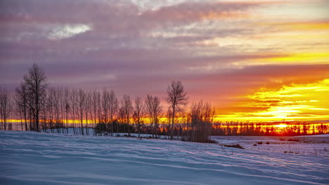Golden-sunset-cloudscape-time-lapse-over-a-snowy,-winter-landscape