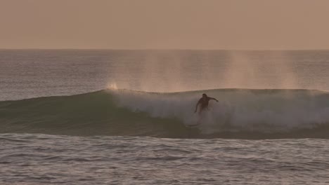 Surfers-catching-waves-at-sunrise-at-Burleigh-Heads-on-the-Gold-Coast,-Australia