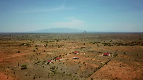 Drone-view-of-a-settlement-of-a-few-modern-houses-and-a-telecommunication-antenna,-on-a-sunny-day,-in-Uganda,-Africa