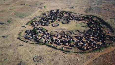 Aerial-view-of-drone-approaching-a-village-in-the-Karamoja-region,-also-called-Manyatta-or-Ere,-in-Uganda,-during-a-sunny-day