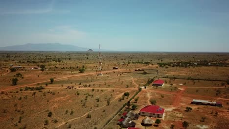 Panoramic-aerial-drone-view-of-an-area-in-Uganda-with-houses-and-a-telecommunication-antenna-on-a-sunny-day