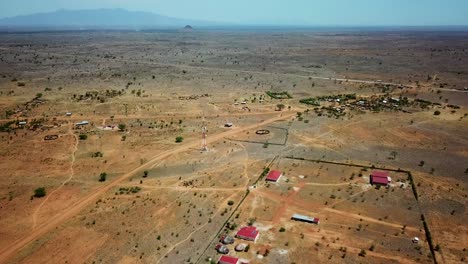 Drone-view-with-general-shot-of-a-settlement-of-a-few-modern-houses-and-a-telecommunication-antenna,-on-a-sunny-day,-in-Uganda,-Africa