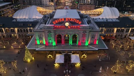 Outdoors-View-of-Denver-Union-Train-Station-at-Evening-illuminated-During-Christmas,-Aerial-Rising-Up-View-of-Colorful-Lights-in-Downtown-District