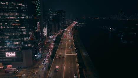 Aerial-backwards-shot-over-busy-highway-in-Kwun-Tong-district-at-night-in-Hong-Kong