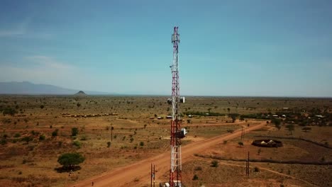 Shot-of-drone-circling-a-telecommunications-antenna-near-a-remote-village-in-Karamoja,-Uganda,-Africa