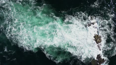Topdown-view-Ocean-waves-breaking-on-submerged-rocks,-Sea-foam-on-Beep-sea