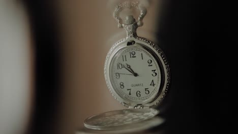 Silver-pocket-watch-moving-in-slow-motion-used-to-induce-a-state-of-hypnosis,-close-up-shot